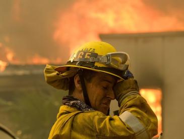 A firefighter in front of a burning structure.