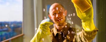 A man in yellow gloves washes a window, as viewed from the other side of the glass.
